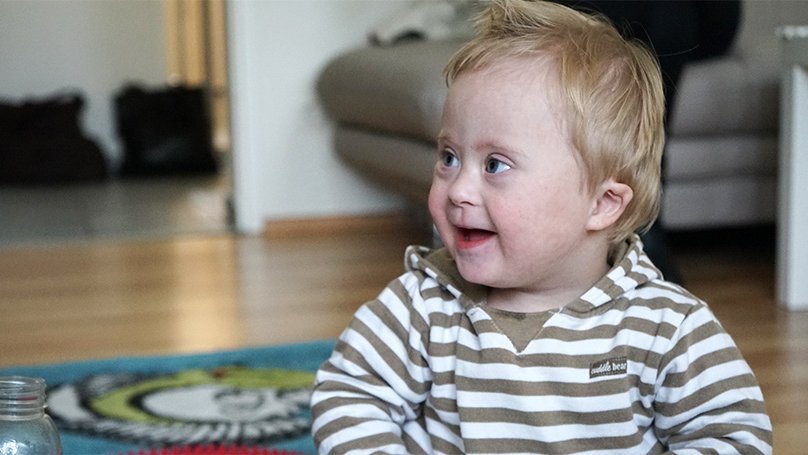 Lachendes Kleinkind mit gestreiftem Kapuzenpullover im Frühförderzentrum
