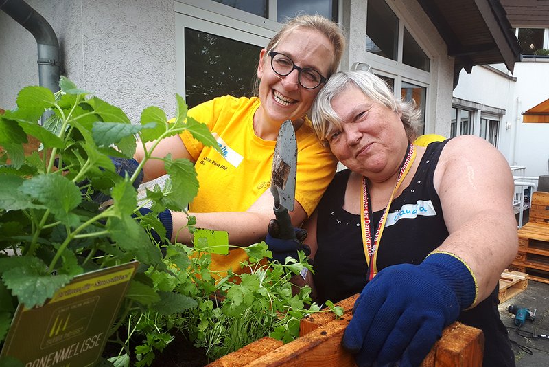 Bewohnerin und Freiwillige bepflanzen ein Beet