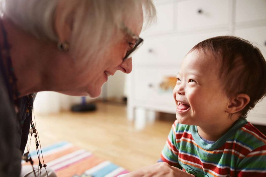 Ein ältere Frau blickt auf ein lachendes Kleinkind.