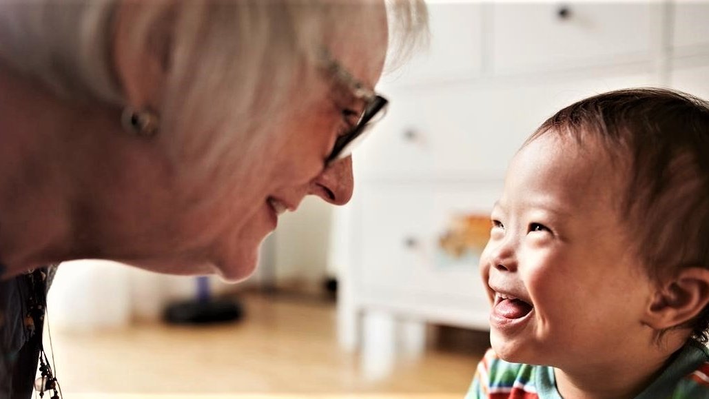 Eine ältere Frau blickt auf ein lächelndes Kleinkind.